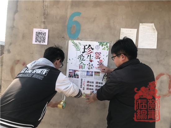 禁毒社工杨毅和张盖张贴禁毒宣传海报